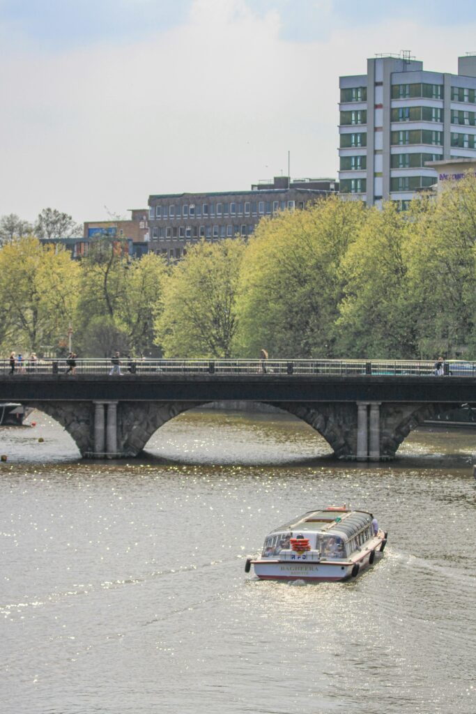 A tranquil scene of a boat on the river passing under a bridge in Bristol, England.