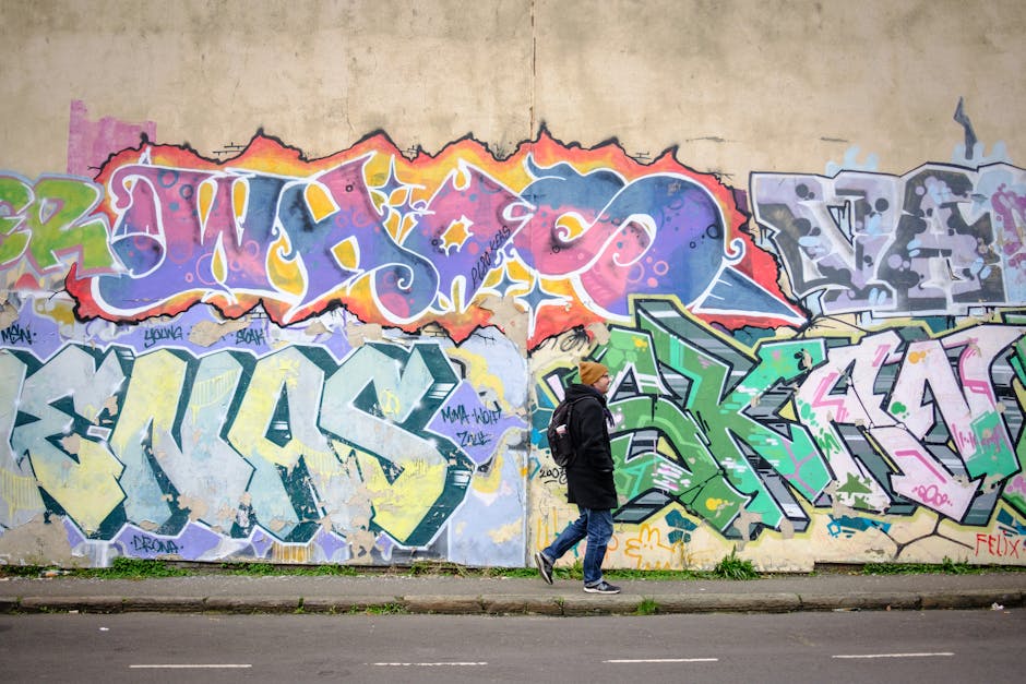 A person walks past vibrant graffiti art on a street wall in Bristol.